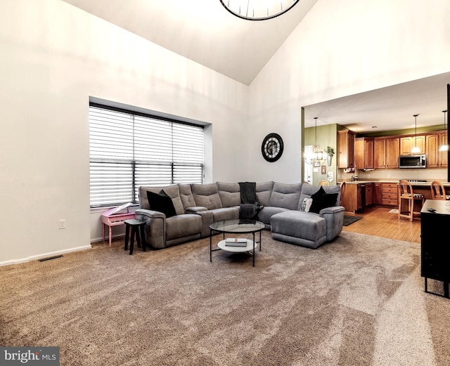 carpeted living room featuring high vaulted ceiling and a notable chandelier