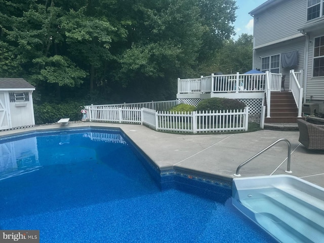 view of swimming pool featuring a wooden deck, a diving board, cooling unit, and a shed