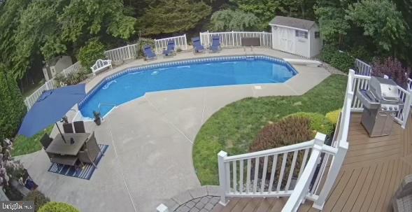 view of swimming pool with a wooden deck and a storage unit