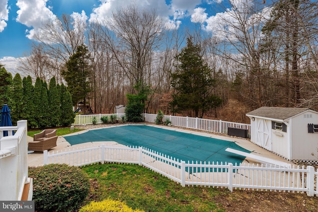 view of pool featuring a diving board and a storage shed