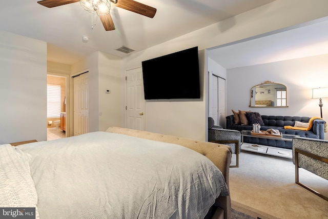 carpeted bedroom with ceiling fan and two closets