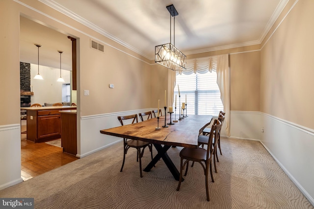 carpeted dining room featuring a chandelier and ornamental molding