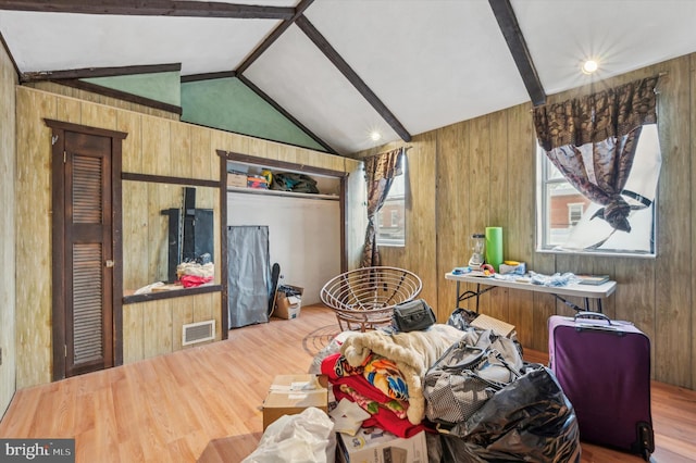 bedroom featuring vaulted ceiling with beams, hardwood / wood-style flooring, and wooden walls