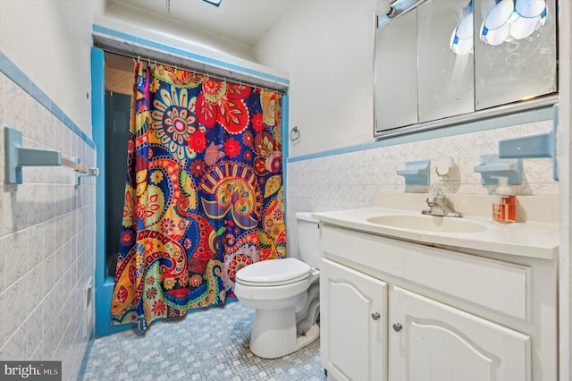 bathroom with vanity, toilet, and tile walls