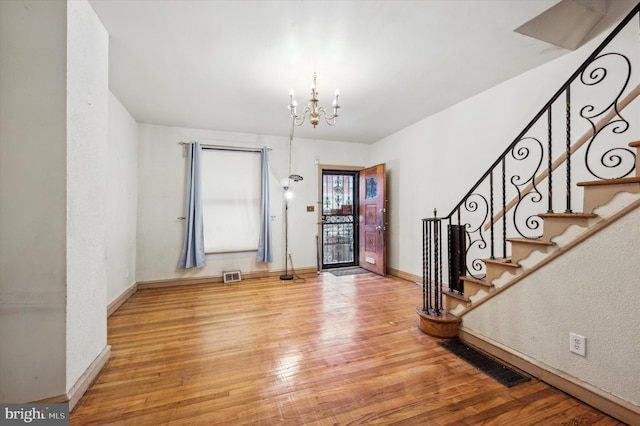 foyer entrance with wood-type flooring and an inviting chandelier