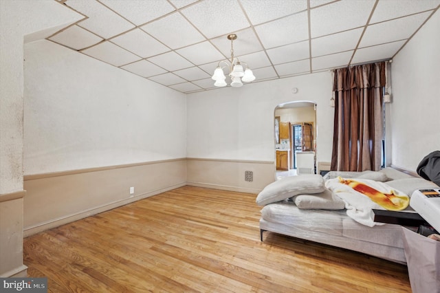 bedroom with a paneled ceiling, hardwood / wood-style flooring, and an inviting chandelier