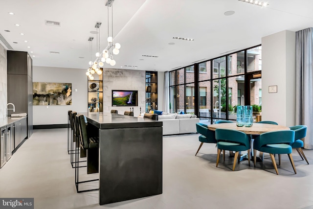 kitchen with a kitchen bar, decorative light fixtures, a wall of windows, and sink