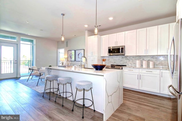 kitchen featuring white cabinets, appliances with stainless steel finishes, and an island with sink