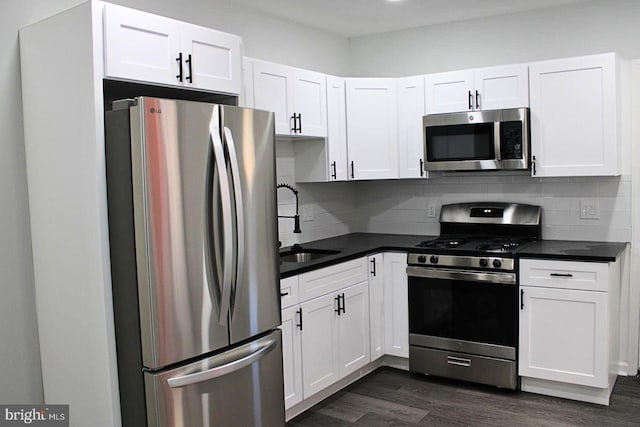 kitchen with white cabinets, dark hardwood / wood-style floors, appliances with stainless steel finishes, and tasteful backsplash