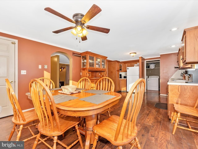 dining area with ornamental molding, ceiling fan, dark wood-type flooring, sink, and washing machine and dryer