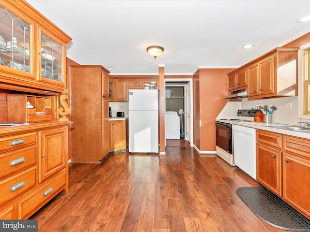 kitchen featuring white appliances, sink, dark hardwood / wood-style floors, washing machine and dryer, and ornamental molding