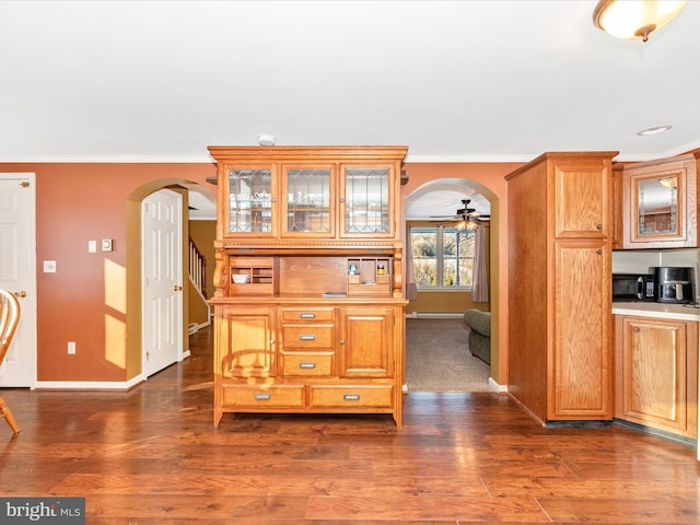 kitchen featuring ceiling fan, crown molding, and dark wood-type flooring