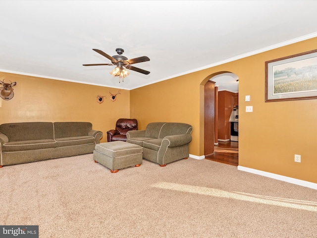 living room featuring carpet, ceiling fan, and crown molding