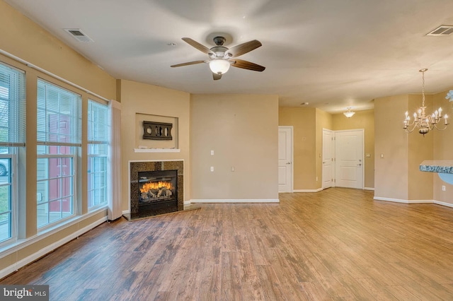 unfurnished living room featuring wood-type flooring and ceiling fan with notable chandelier