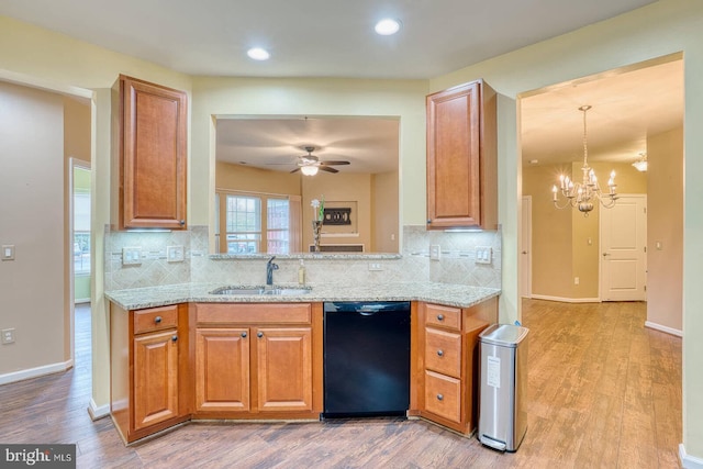 kitchen with sink, black dishwasher, decorative backsplash, ceiling fan with notable chandelier, and light wood-type flooring