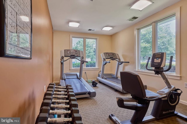 workout area with dark colored carpet and a wealth of natural light