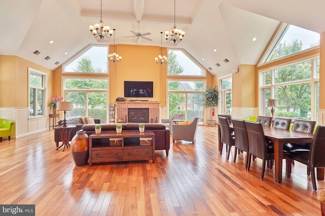 living room with a fireplace, a towering ceiling, light hardwood / wood-style floors, and ceiling fan