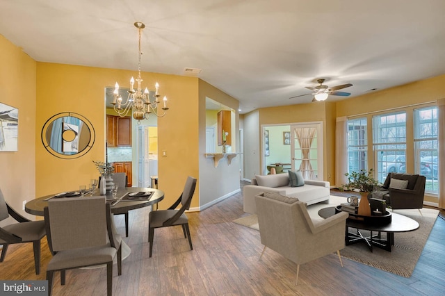 living room with ceiling fan with notable chandelier and hardwood / wood-style flooring