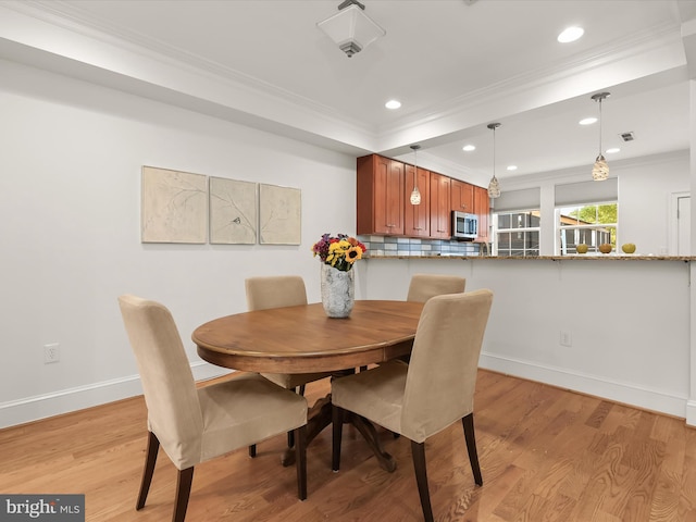 dining area featuring ornamental molding and light hardwood / wood-style flooring