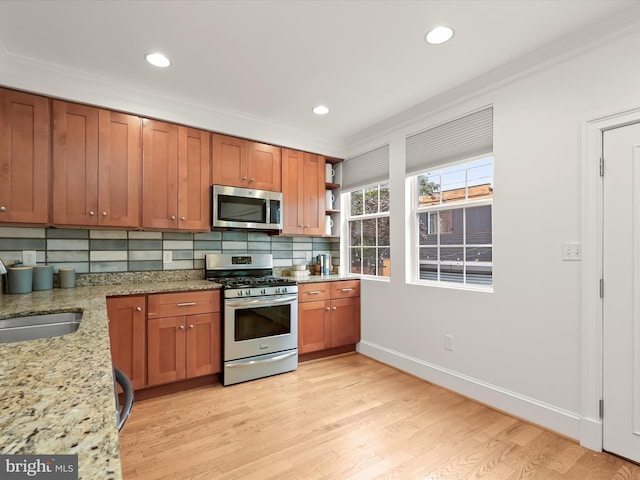 kitchen featuring light stone countertops, crown molding, and stainless steel appliances