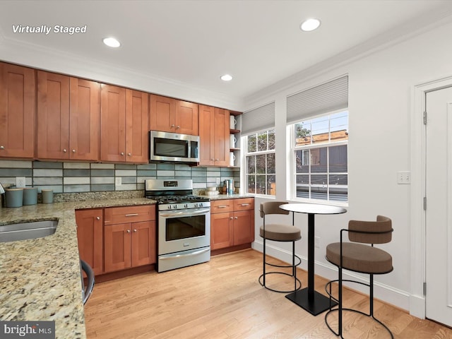 kitchen with light stone counters, crown molding, and stainless steel appliances