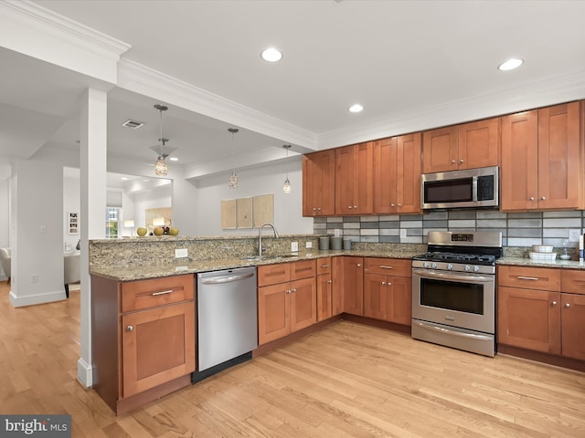 kitchen with sink, light stone countertops, decorative light fixtures, kitchen peninsula, and stainless steel appliances