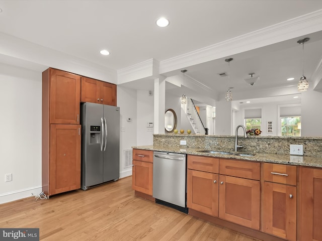 kitchen with decorative light fixtures, light stone countertops, sink, and appliances with stainless steel finishes