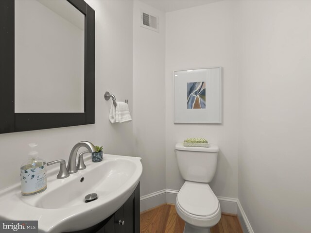 bathroom with hardwood / wood-style floors, vanity, and toilet