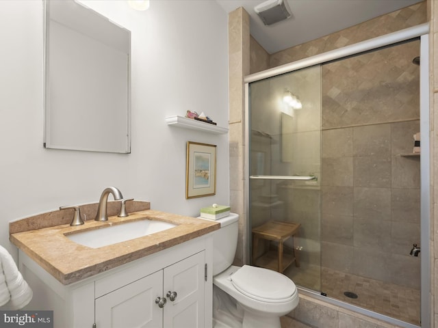 bathroom featuring a shower with door, vanity, and toilet