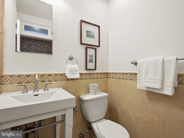 bathroom with toilet, tile walls, and sink