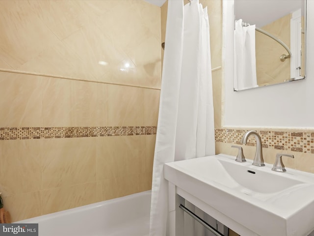 bathroom featuring sink, shower / bathtub combination with curtain, and backsplash