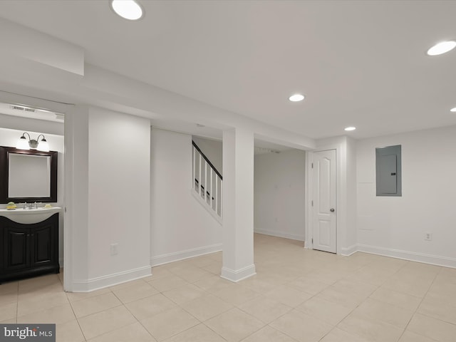 basement with light tile patterned floors, sink, and electric panel