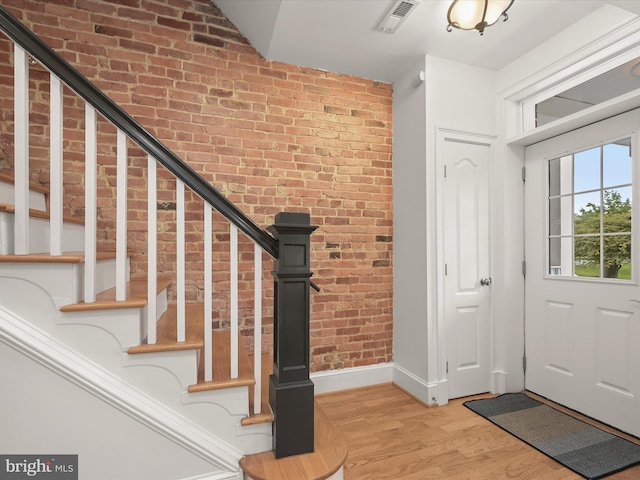 entryway with light hardwood / wood-style floors and brick wall