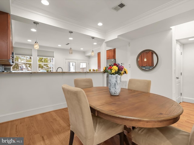 dining space with crown molding, light hardwood / wood-style flooring, and french doors