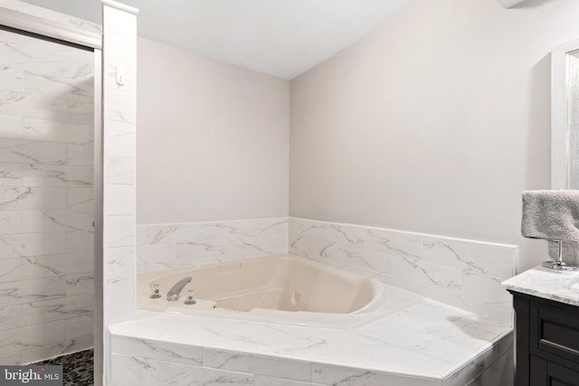 bathroom featuring tiled bath and vanity