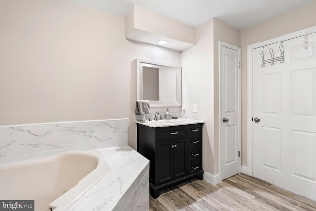 bathroom featuring vanity, hardwood / wood-style flooring, and tiled tub