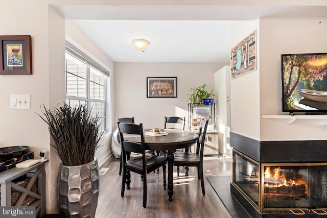 dining space with hardwood / wood-style flooring and a multi sided fireplace