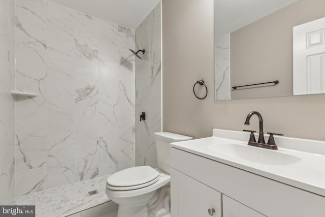 bathroom with tiled shower, vanity, and toilet