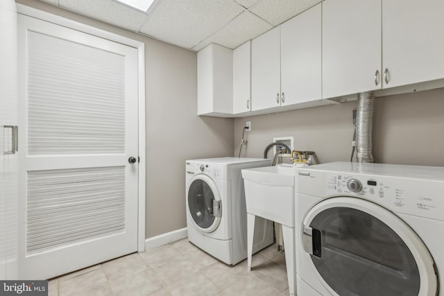 laundry area featuring separate washer and dryer, cabinets, and light tile patterned floors