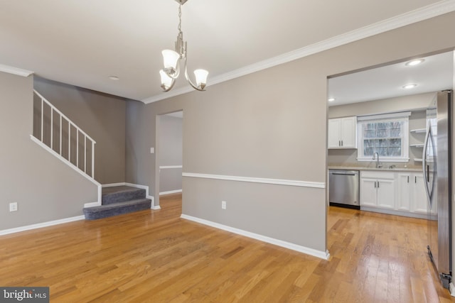 interior space with a notable chandelier, light hardwood / wood-style floors, ornamental molding, and sink