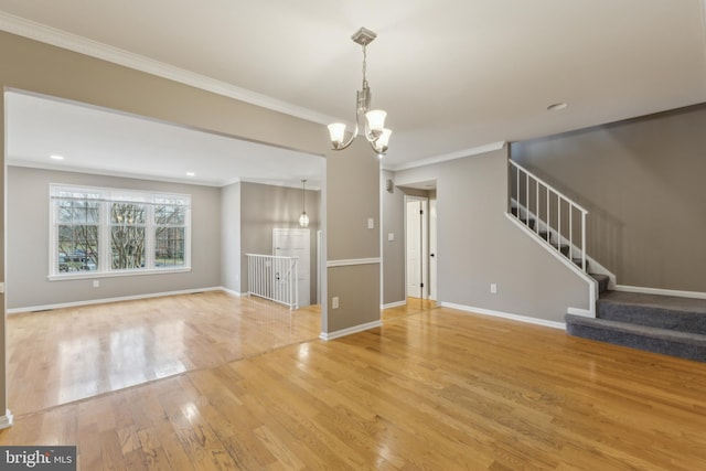 unfurnished living room with an inviting chandelier, crown molding, and hardwood / wood-style flooring