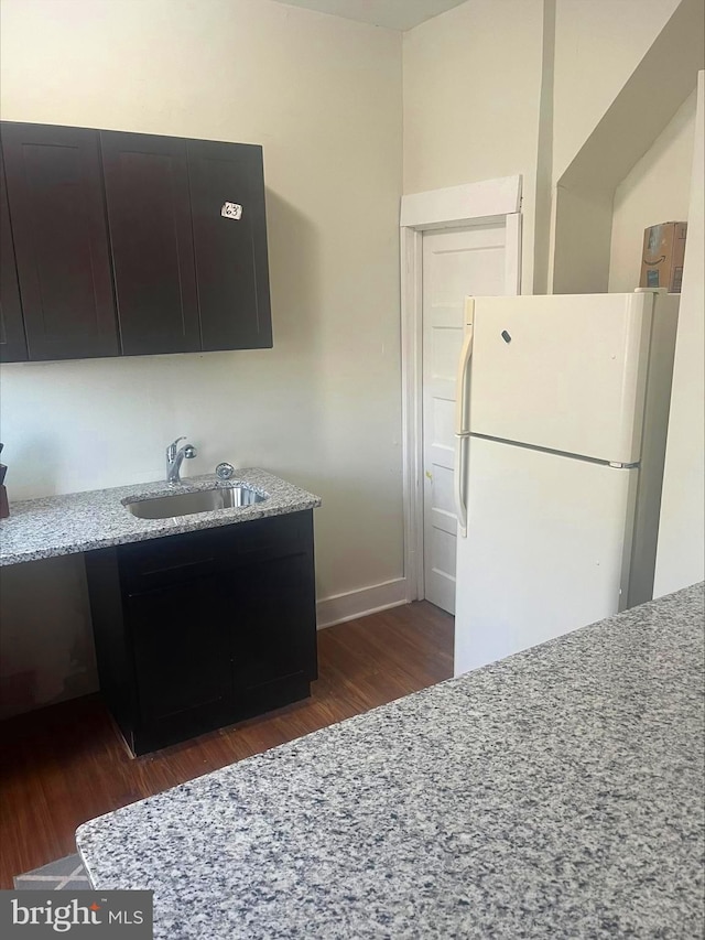 kitchen with light stone countertops, white refrigerator, and sink