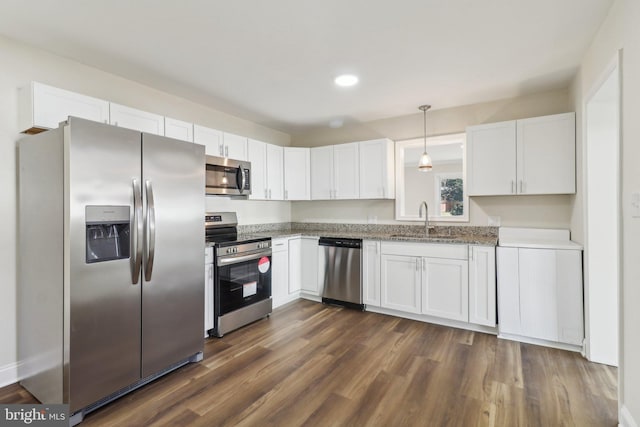 kitchen featuring stainless steel appliances, sink, white cabinets, dark hardwood / wood-style floors, and hanging light fixtures