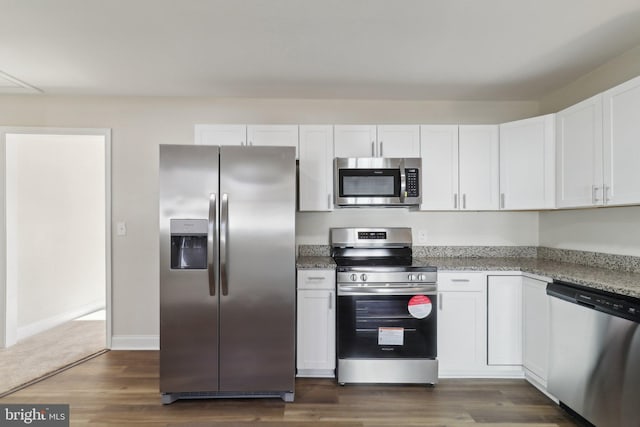 kitchen featuring white cabinets, appliances with stainless steel finishes, dark hardwood / wood-style flooring, and dark stone counters