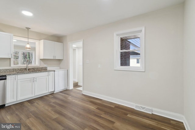 kitchen featuring white cabinets, decorative light fixtures, stone countertops, and sink