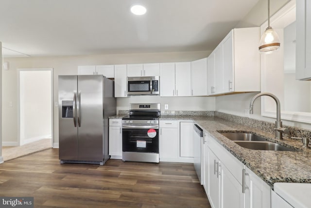 kitchen featuring appliances with stainless steel finishes, sink, pendant lighting, stone counters, and white cabinetry