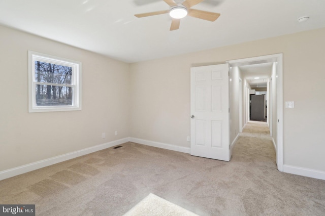 spare room with ceiling fan and light colored carpet