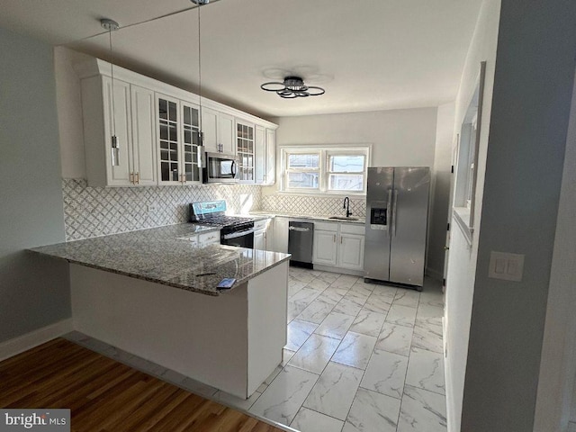 kitchen featuring sink, white cabinetry, kitchen peninsula, stone counters, and stainless steel appliances