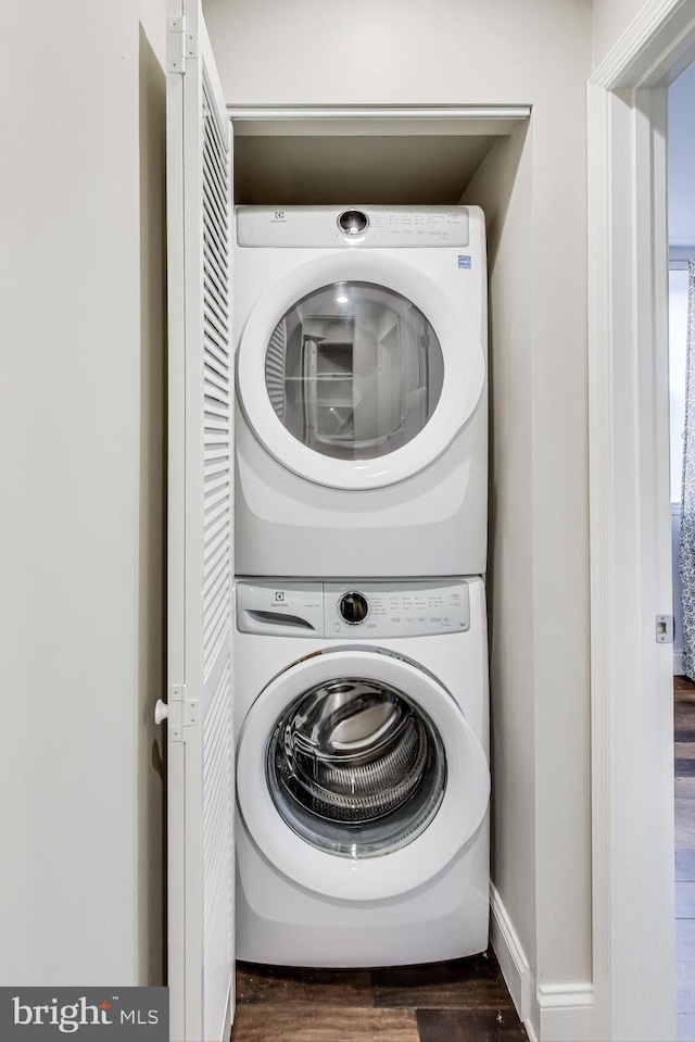 washroom featuring dark hardwood / wood-style flooring and stacked washer and dryer