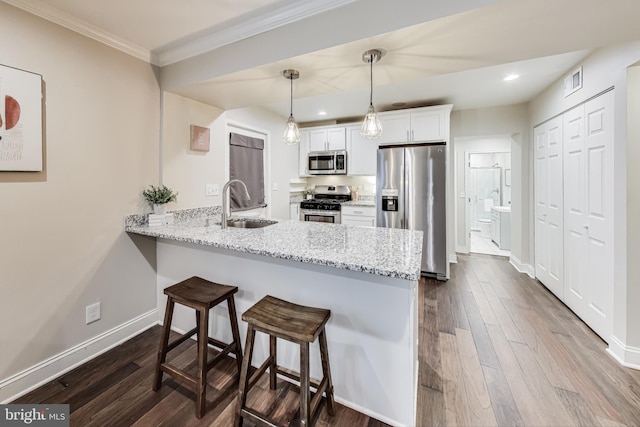 kitchen featuring sink, stainless steel appliances, kitchen peninsula, pendant lighting, and white cabinets